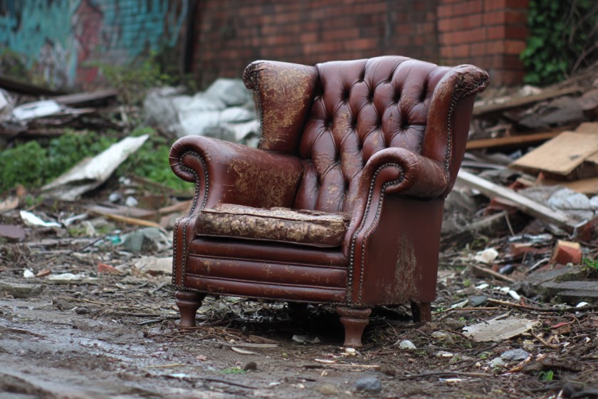 a battered old leather armchair dumped on waste ground
